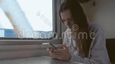 疲惫的年轻女子在火车上看手机。